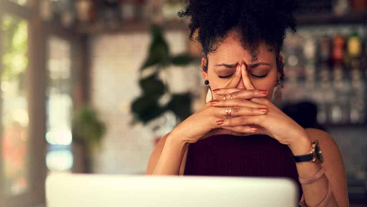 Black woman in front of her laptop suffering from migraine